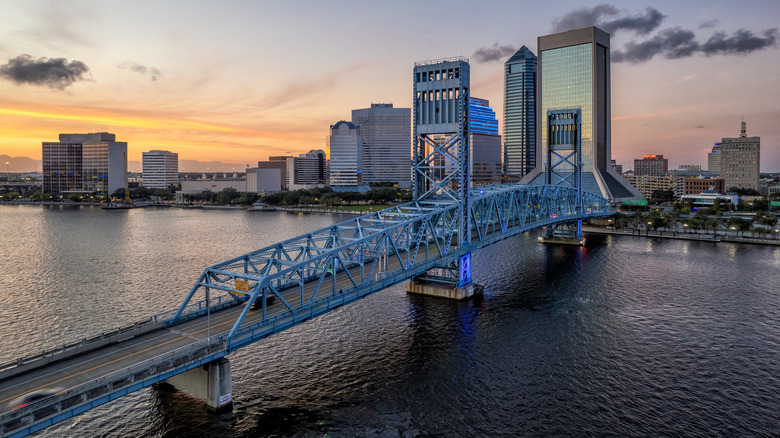 St Johns River flowing through Jacksonville with city skyscrapers and a bridge during dusk.