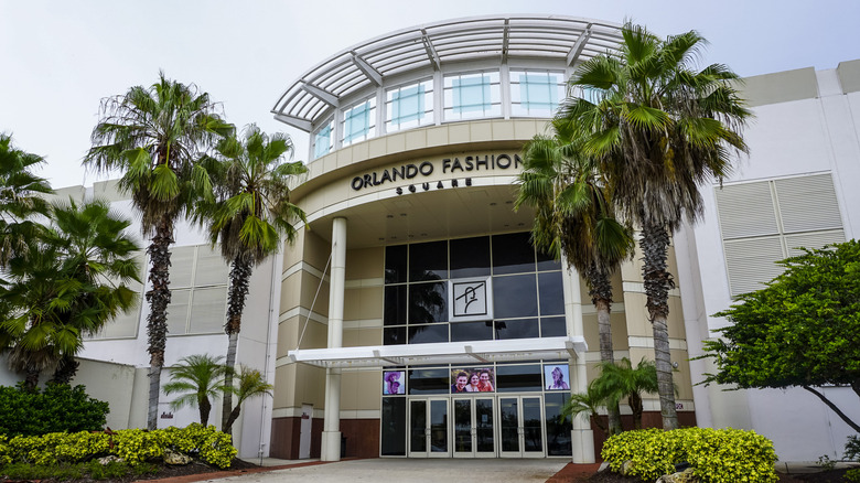 The front entrance of Orlando Fashion Square mall with palm trees and plants