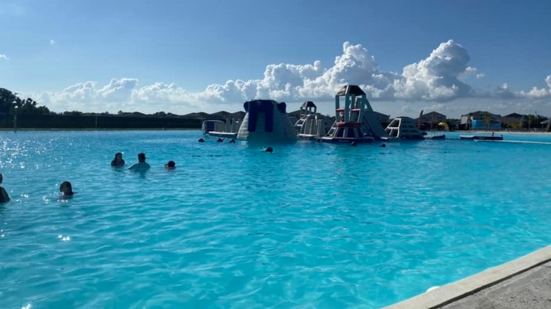 People relaxing in the pool and an obstacle course in the background