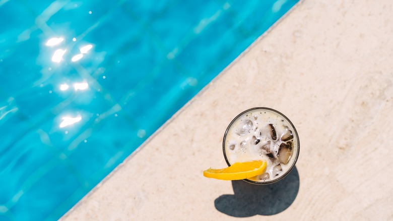A cocktail rests by the edge of a pool