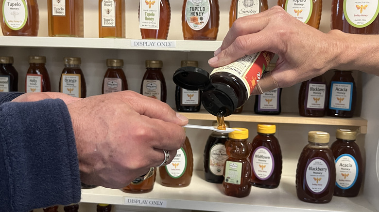 Hand pouring Tupelo honey onto sampling spoon at Smiley Honey in Wewahitchka, Florida