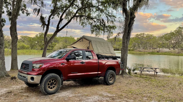 Red truck parked in front of a tent with a lake in the background in Florida
