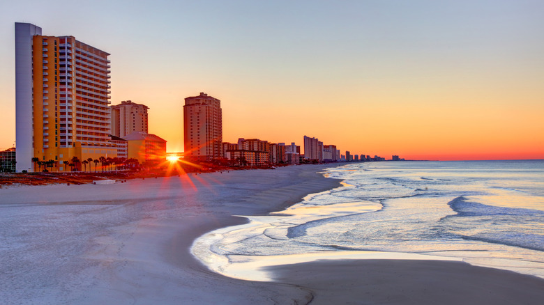 The sun sets behind resorts along Panama City Beach, Florida.