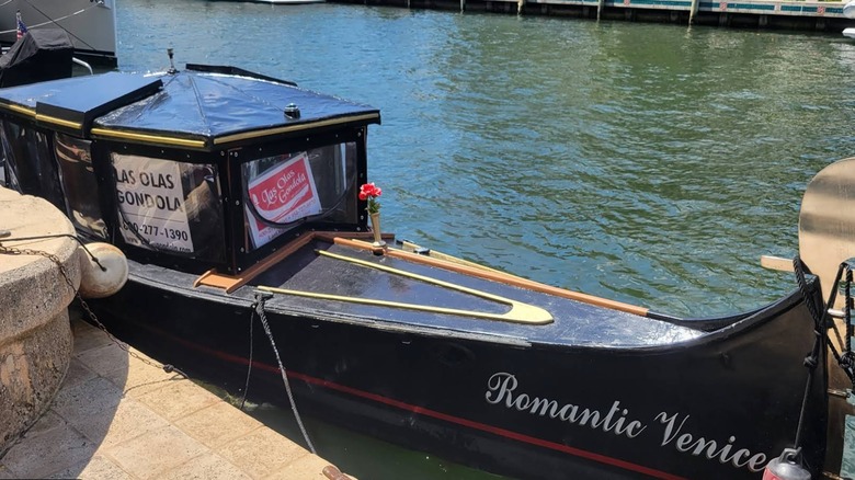 A gondola  that says "Romantic Venice" on the side docked in the water