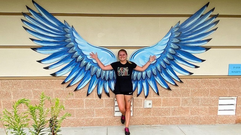 girl standing in front of blue wings