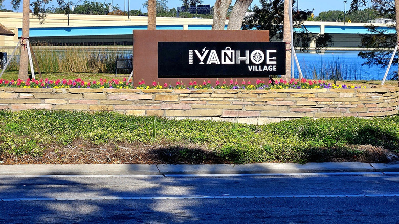 Sign that says Ivanhoe Village with flowers in front