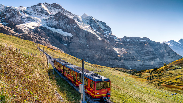 Red train on the Jungfrau railway with the Jungfrau mountain in the background in the Bernese Alps in Switzerland
