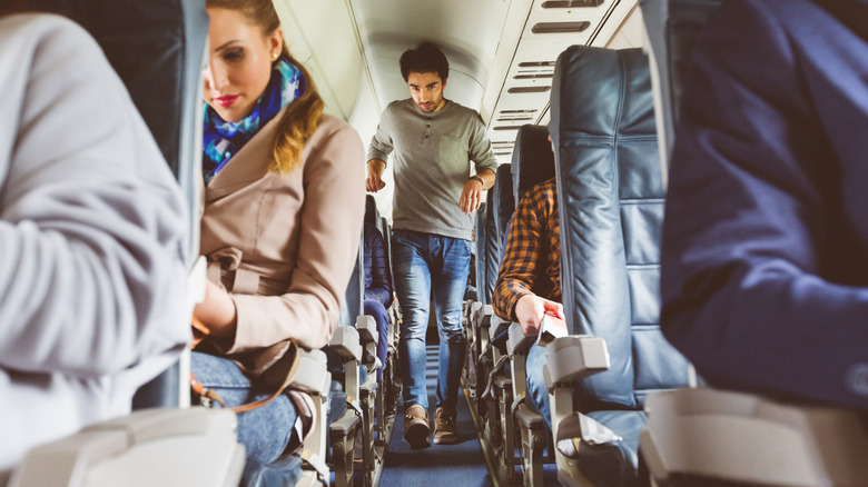 A crowded plane with air vents visible overhead