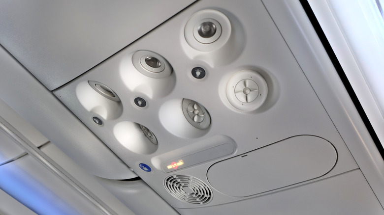 An overhead air vent above a row of plane seats