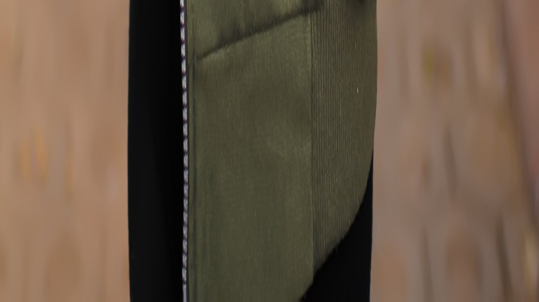 A woman wearing a white T-shirt, bomber jacket, and black pants.