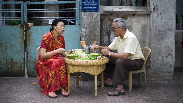 Couple enjoying pho at a table outside of a cafe in Ho Chi Minh, Vietnam