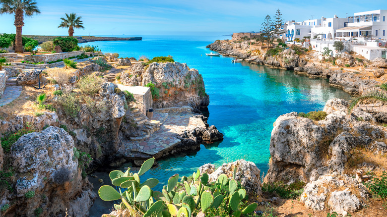A pocket beach in Avlemonas with bright blue water, rocky cliffs, and houses in the background.