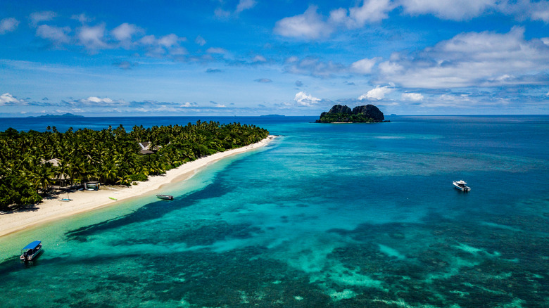Aerial view of the beaches in Fiji's Vomo Island, with boats in the water