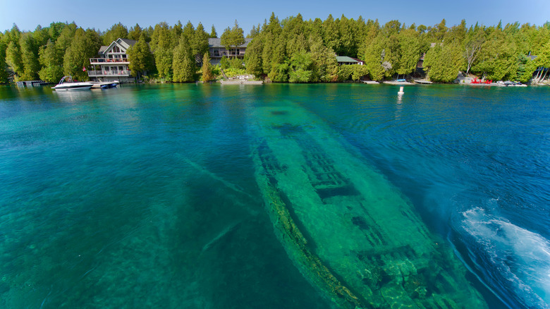 A wreck rests directly beneath the surface of turquoise waters in Fathom Five National Marine Park, Canada