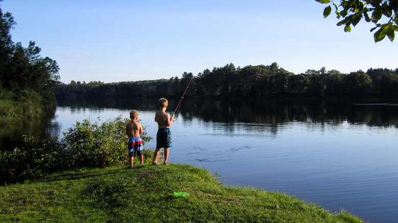 Two young boys cast fishing lines into a river on a sunny summer day in Skowhegan, Maine