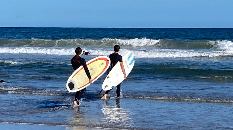 Two surfers carrying boards into the waters of Rhode Island's Narragansett Bay