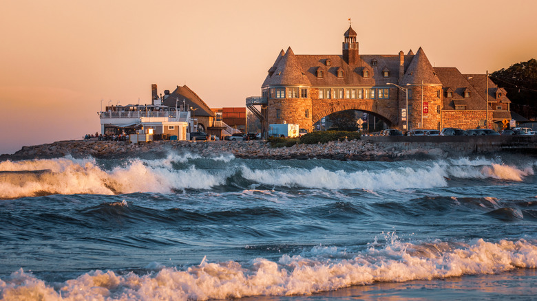 Waves roll into Narragansett Beach in Rhode Island as the sunset casts a stone structure in an orange glow