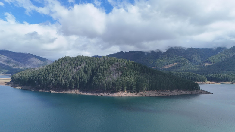 Aerial drone view of Detroit Lake Oregon with turquoise reservoir water, exposed shoreline, forested mountains and low water levels