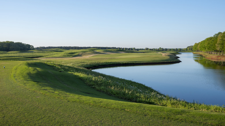 A long green fairway beside a pond and trees on a Robert Trent Jones Golf Trail course in Alabama