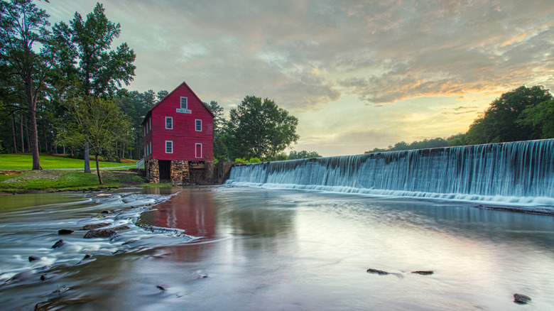 Backed by trees, the red, wooden Starr's Mill sits next to a waterfall in Fayette County, Georgia