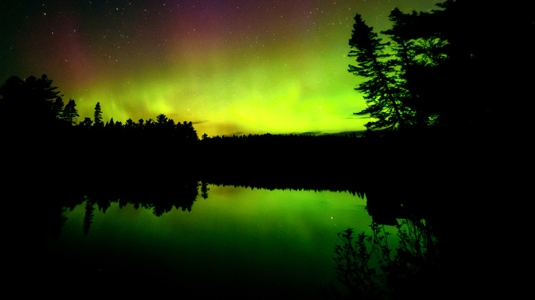 Stars and yellowy-green Northern Lights reflected in Moosehead Lake in Maine