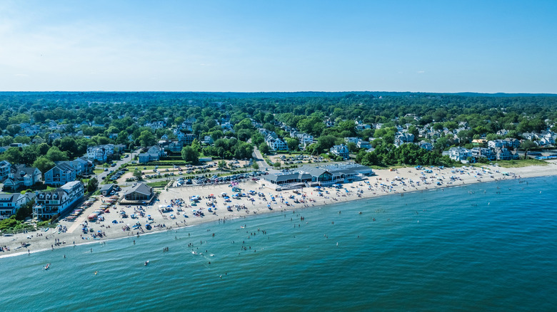 A beach full of people on a bright, clear day, surrounded by the tree-filled city of Fairfield in Fairfield County, Connecticut