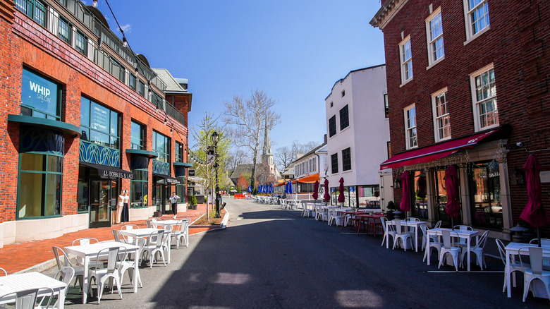 A partially shaded lane lined with eateries and buildings on a clear day in Westport, Connecticut