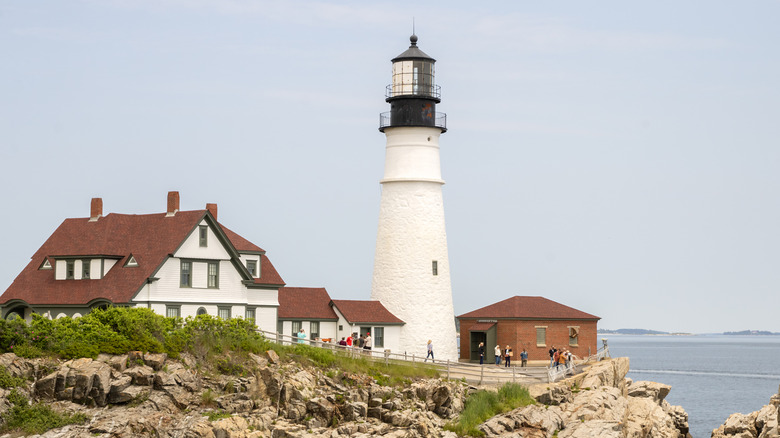 The white body of the Portland Head Lighthouse stands out against a blue-gray sky