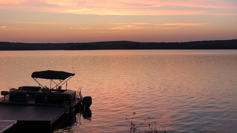A boat docked at the jetty on Damariscotta Lake during a pink and purple sunset.