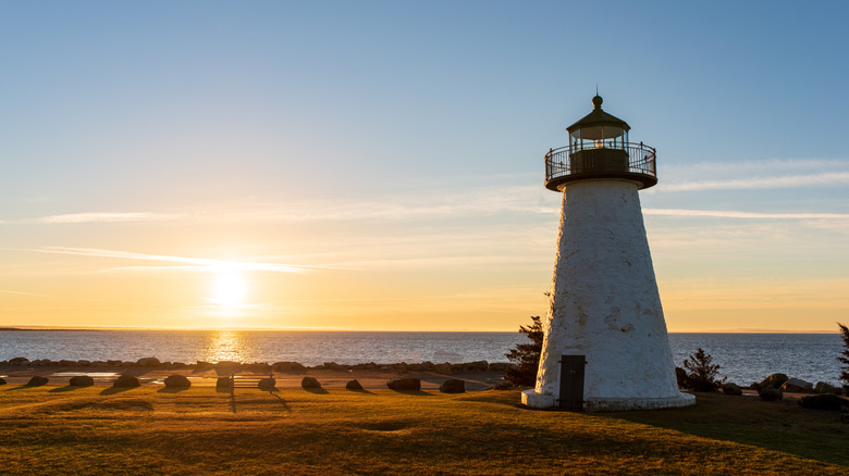 Ned's Point Lighthouse stands before a golden, beachside sunrise in Plymouth County, Massachusetts