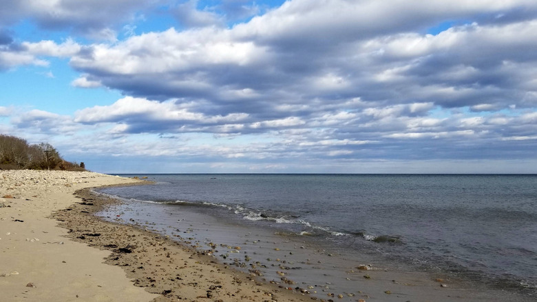 Dense, silver stratus clouds hover low above a calm, gray sea on a winter day at Plymouth County's Center Hill Preserve in Massachusetts