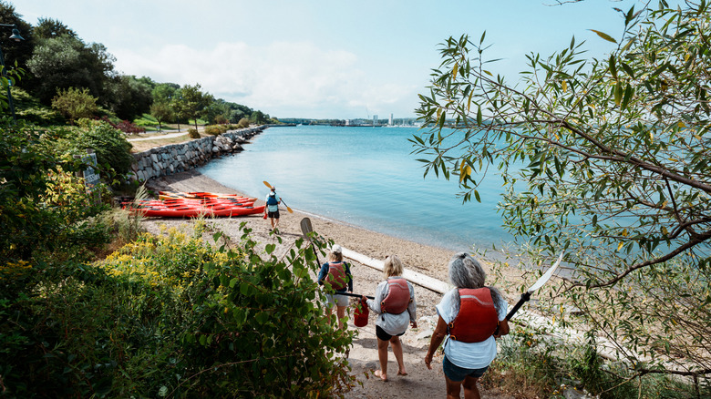 Senior kayakers walking down a beach trail in New England