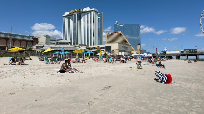 People sit on the beach below large high rise buildings