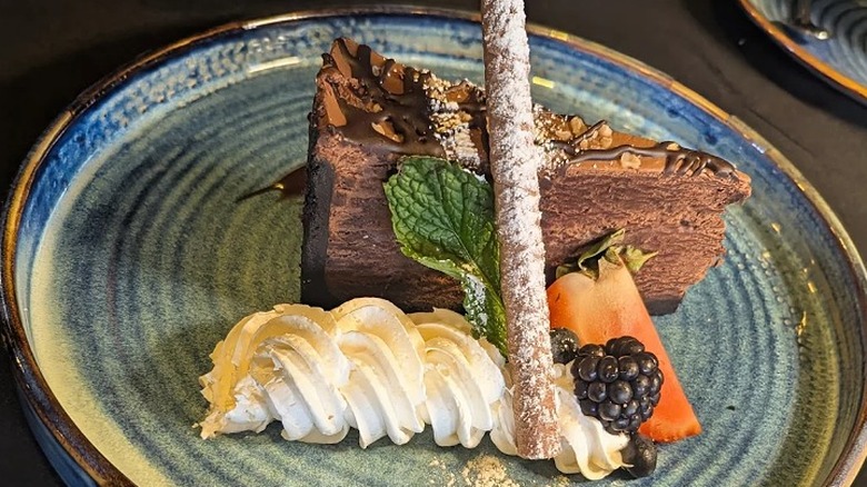 A rich chocolate cake with cream and berries on a plate at Pithari in Middletown.