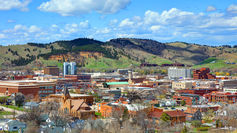 Rapid City in Pennington County, South Dakota, with pine-covered hills behind the city's buildings