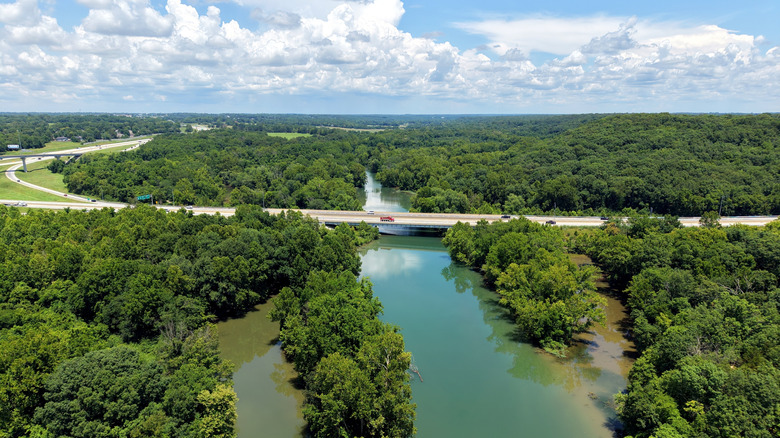 A scenic Missouri Ozarks vista capturing a river, forest, roads, and cloudy sky