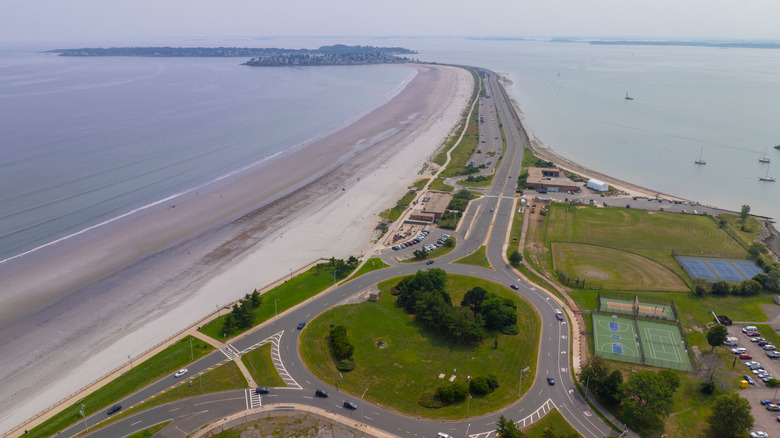 Aerial view of Nahant Beach's long stretch of sand beside the road with boats on the water, in Massachusetts