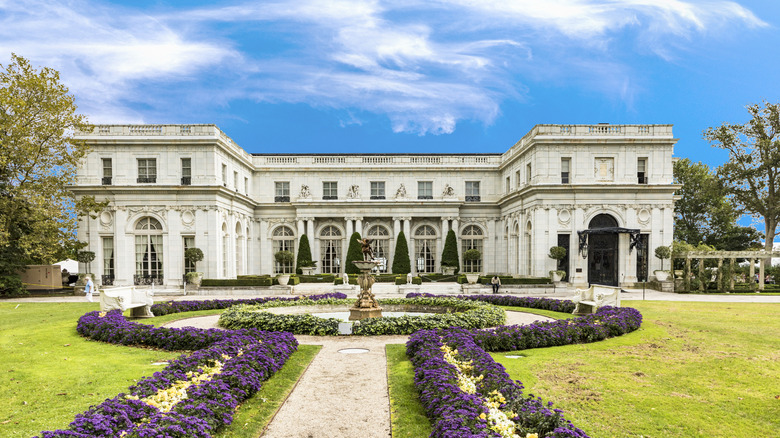 On a sunny day, manicured flowers lead up to a mansion in Newport, Rhode Island