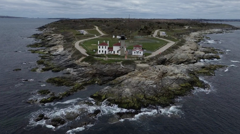 An aerial view of waves washing up on cliffs in front of Beavertail Lighthouse in Rhode Island