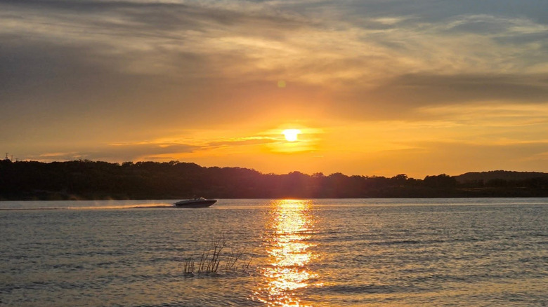 A boat racing across a lake at sunset in Lago Vista, Texas