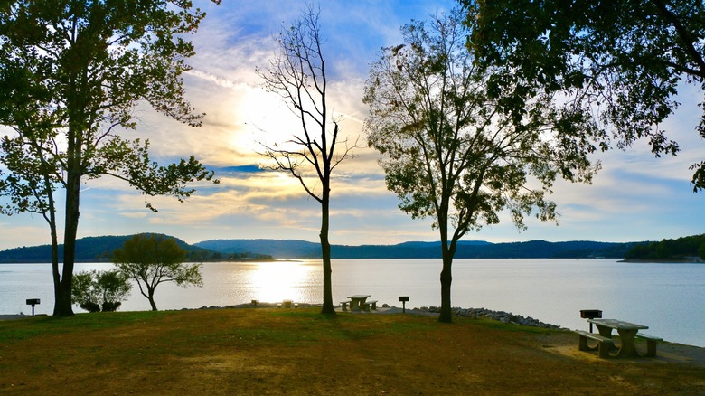 The sun low in the sky over a calm Bull Shoals Lake seen from a lakeside park