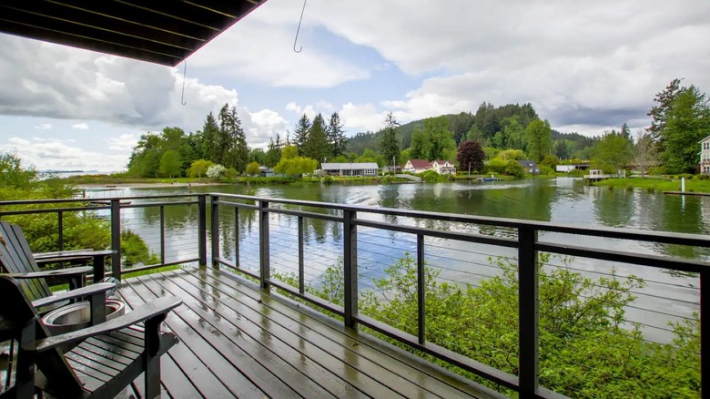 View of the Columbia River from a covered wooden deck with two Adirondack chairs; across the river are homes and short mountain in the distance