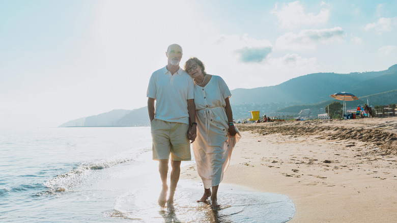 Happy senior couple walking on a beach hand in hand