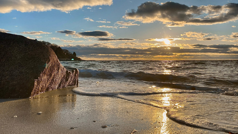 Sunset at Old Silver Beach on Cape Cod with golden light reflected in the lapping waves on shore