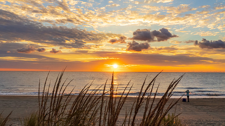 An idyllic sunrise over water with colorful clouds at Rehoboth beach in Delaware.
