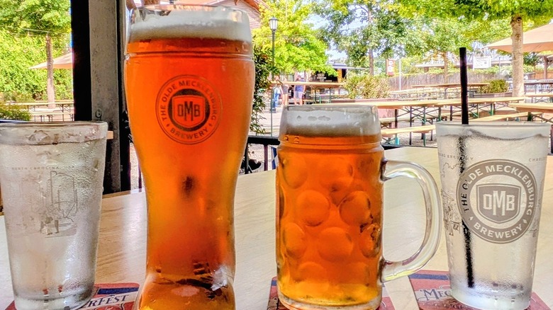Two beer steins filled with beer on a table in the outdoor beer garden at Olde Mecklenburg Brewery