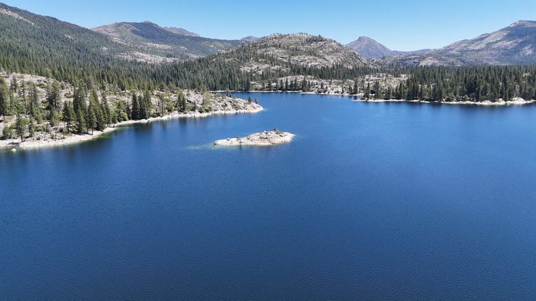 Bright-blue Lake Spaulding in California surrounded by snowy peaks dotted with conifers