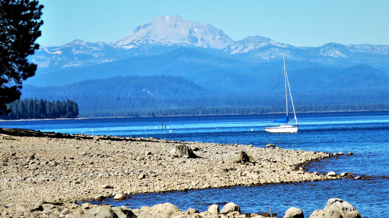 A sailboat anchored off the shore of Lake Almanor, with Lassen Peak in the background