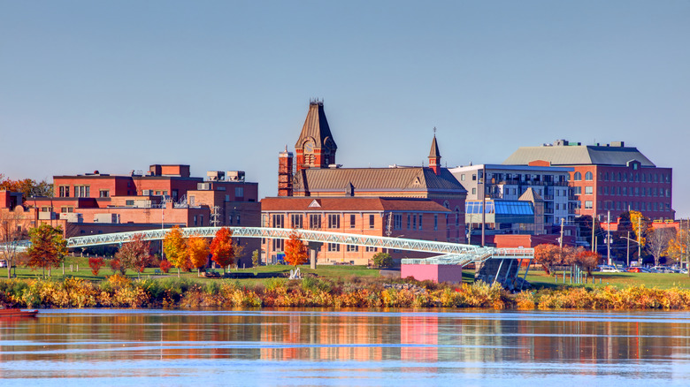 Brick-red buildings are mirrored in the water's reflection against a big blue sky in Fredericton, New Brunswick, Canada