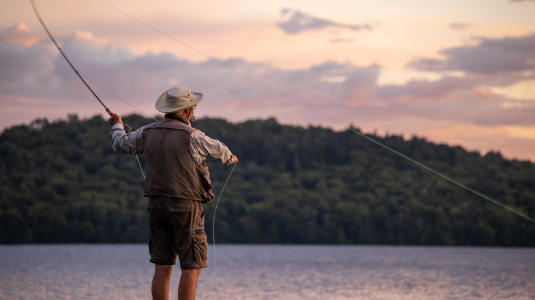 A senior man fishing at a lake in Quebec during sunset